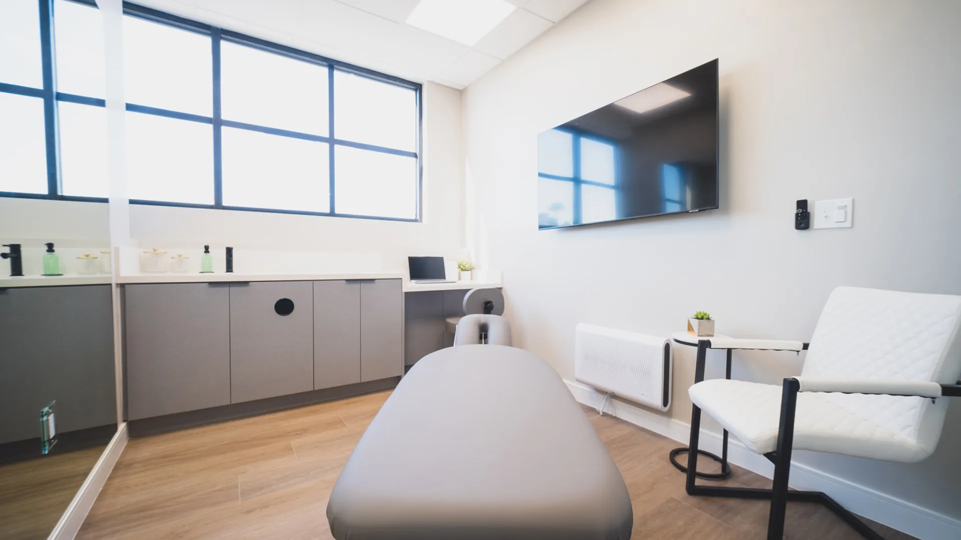 Consultation and treatment room at Aviara Centers with exam table, large window, wall-mounted screen, and patient seating